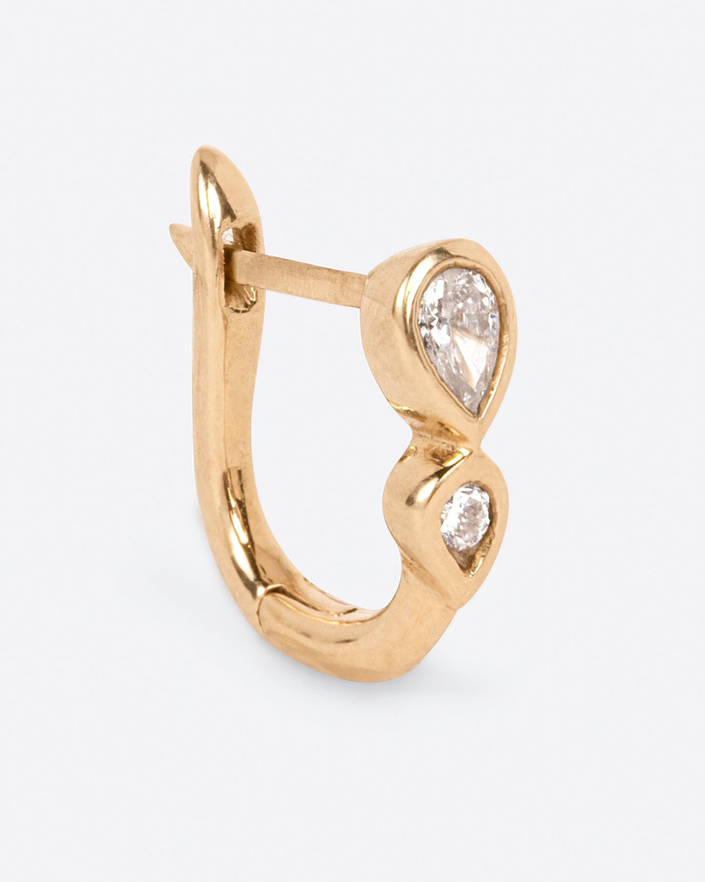 A huggie hoop earring with a pair of stacked pear shaped diamonds.