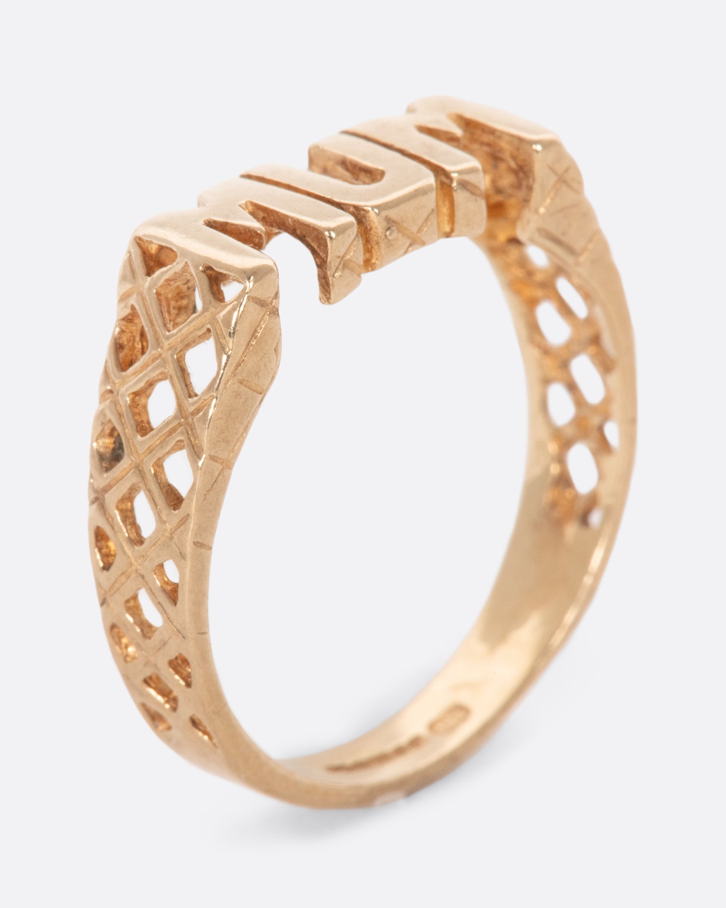 Gold ring that reads 'MUM' with crosshatch retail on either side. View from the side.