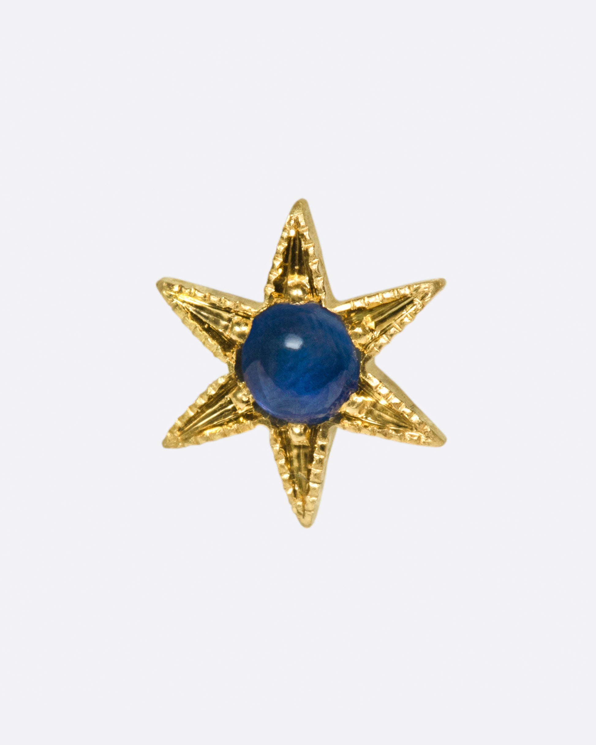 A celestial stud with a deep blue sapphire cabochon at its center.