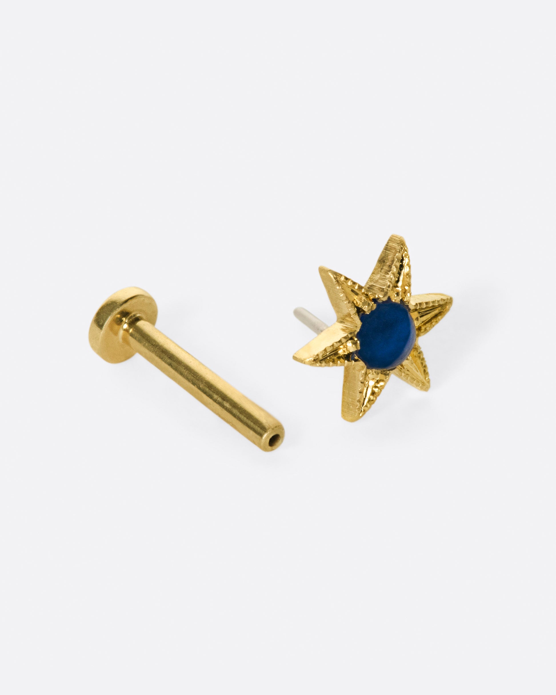 A celestial stud with a deep blue sapphire cabochon at its center.