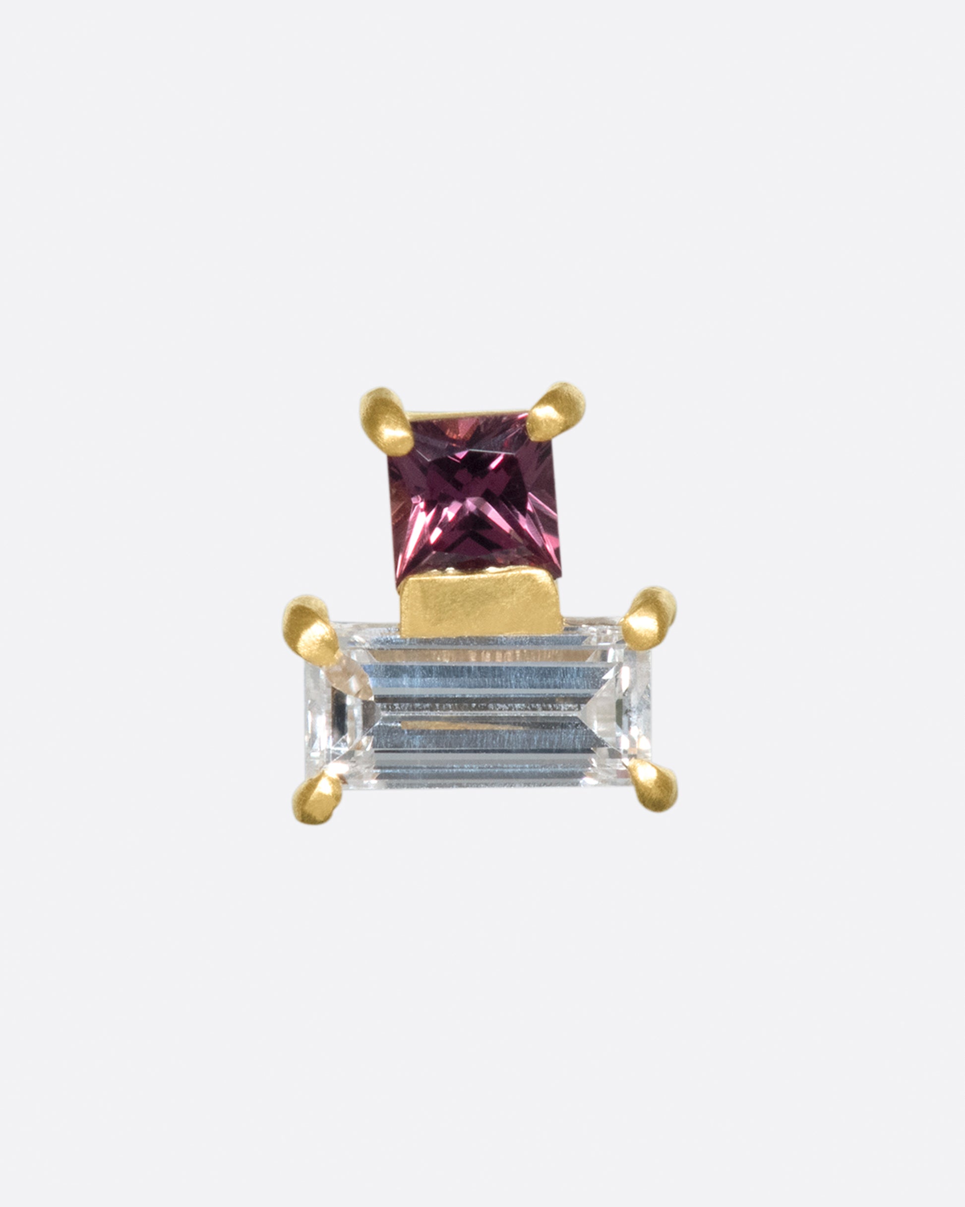 A princess cut, mauve-y pink sapphire sits centered atop a diamond baguette. That said, this piece looks beautiful at every angle.