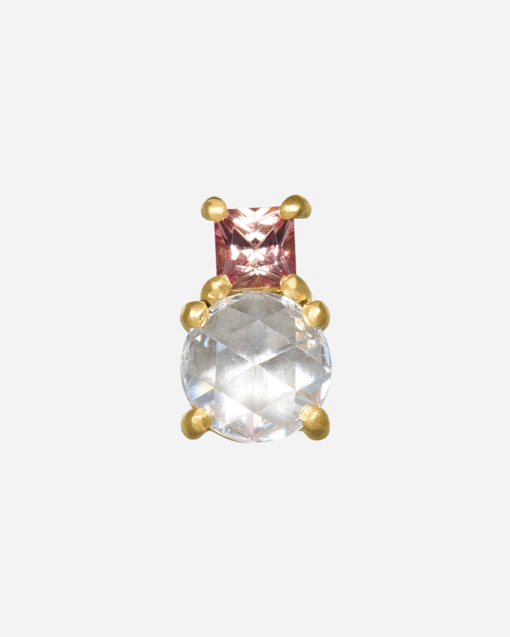 An uncommon combination; a rose cut diamond with a peachy pink princess cut sapphire.