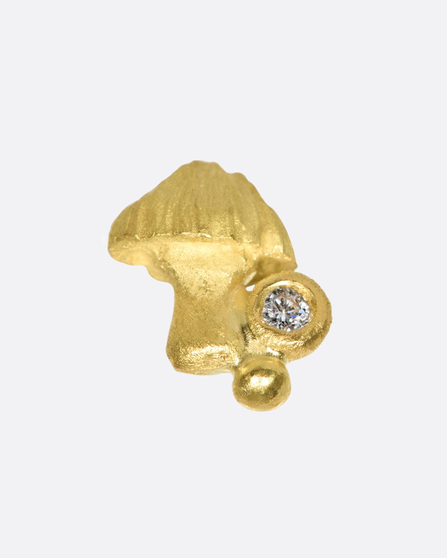 Matte gold and hand carved, this little fungus remains subtle on the ear.