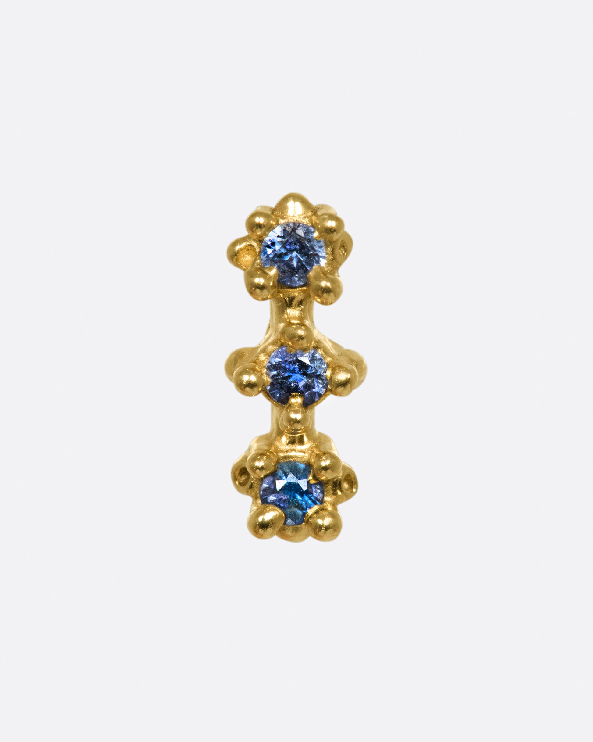 Three blue sapphires form the core of this bar stud, but their textured settings make sure that the style is anything but simple.
