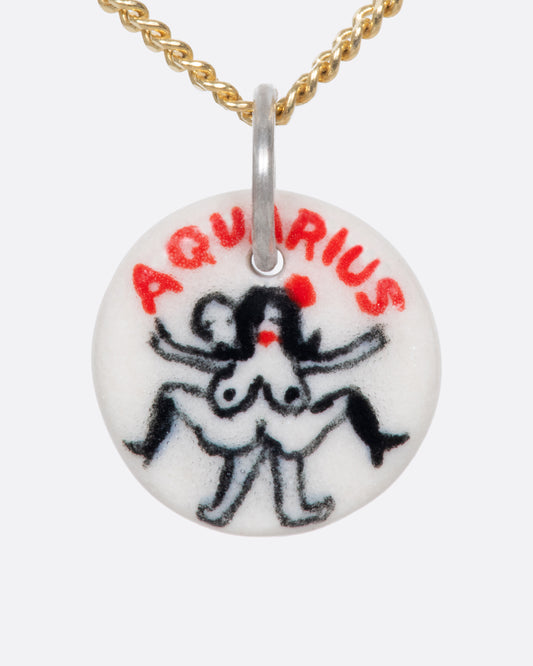 A handmade and painted porcelain zodiac disc charm with a sterling silver bail, featuring a sex position specific to each zodiac.