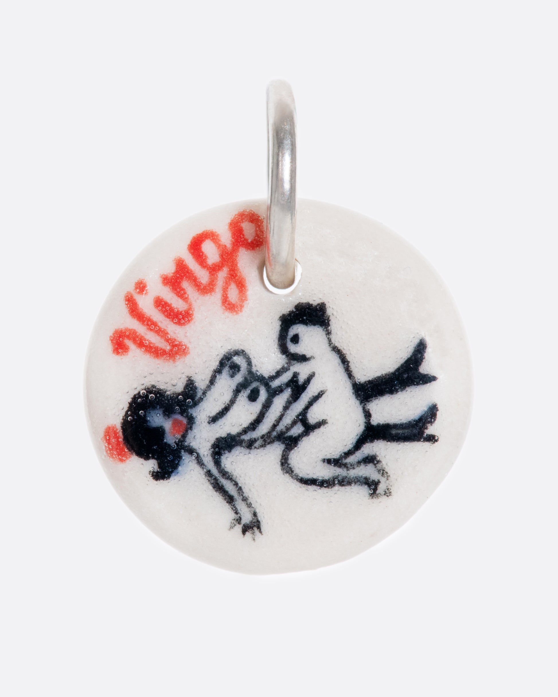 A handmade and painted porcelain zodiac disc charm with a sterling silver bail, featuring a sex position specific to each zodiac.