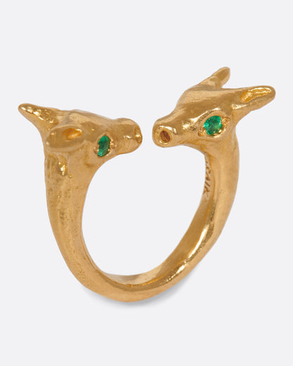 Yellow gold animal head ring with emerald eyes, angled view of the two animal heads facing each other at the opening