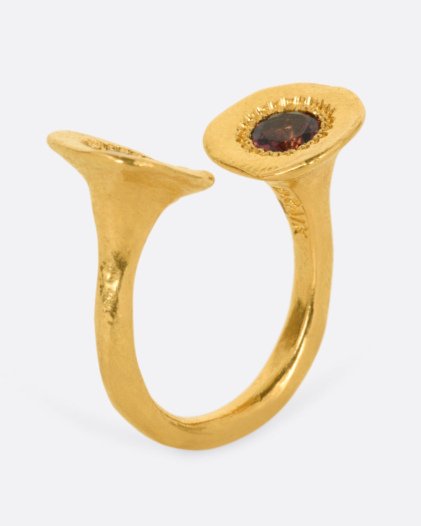 A high karat gold open ring with a large organic shaped disc on each end with a rosey pink tourmaline at its center. Shown from the side.