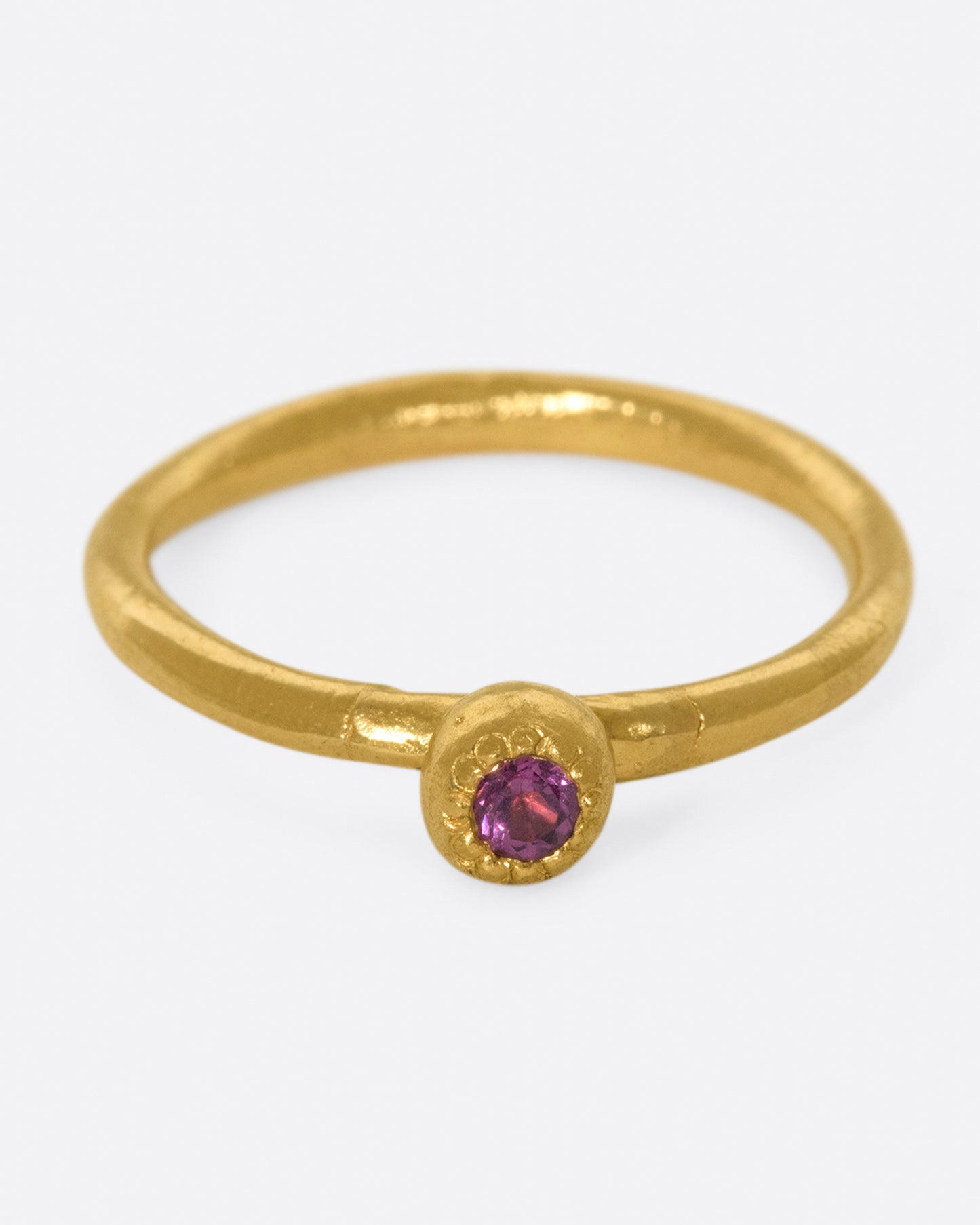 A high karat gold solitaire ring with a rosy pink tourmaline at its center.
