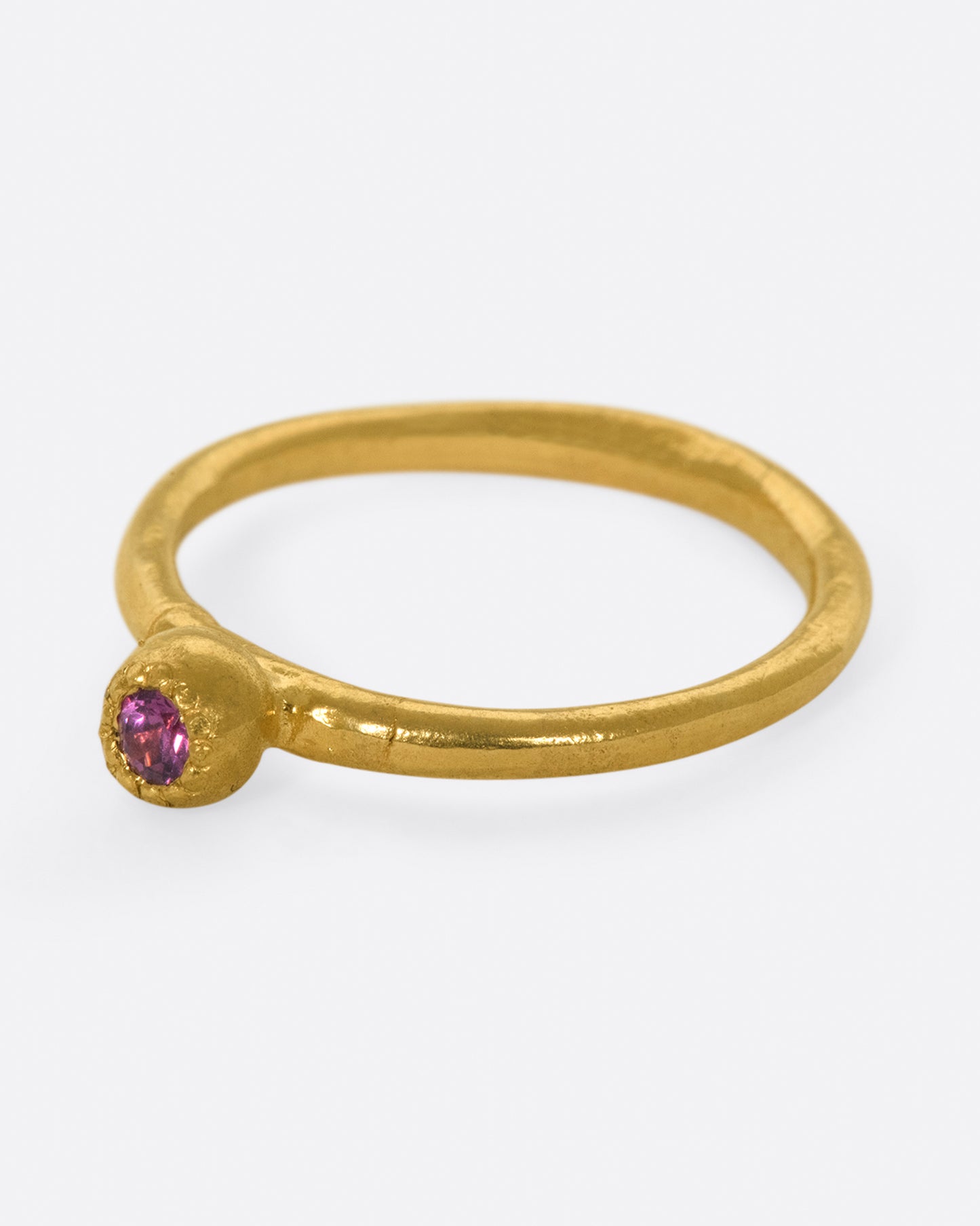 A high karat gold solitaire ring with a rosy pink tourmaline at its center.
