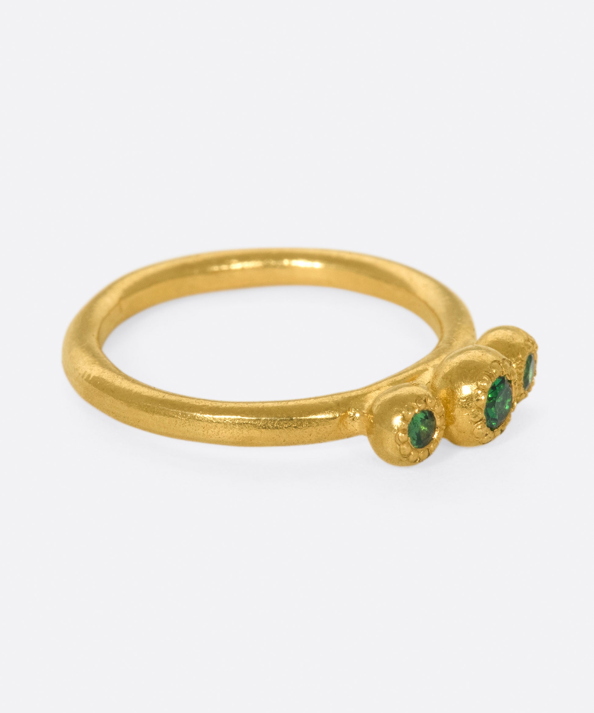 A hand sculpted three stone ring with vivid green tsavorite garnets.
