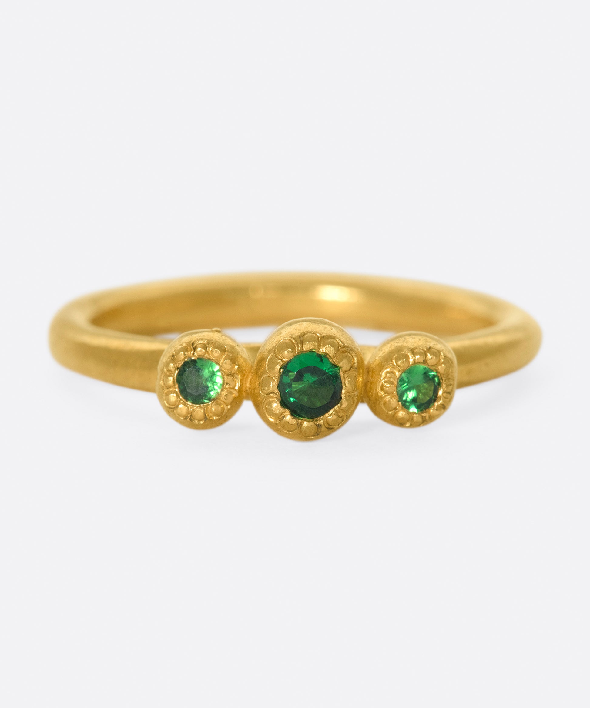 A hand sculpted three stone ring with vivid green tsavorite garnets.