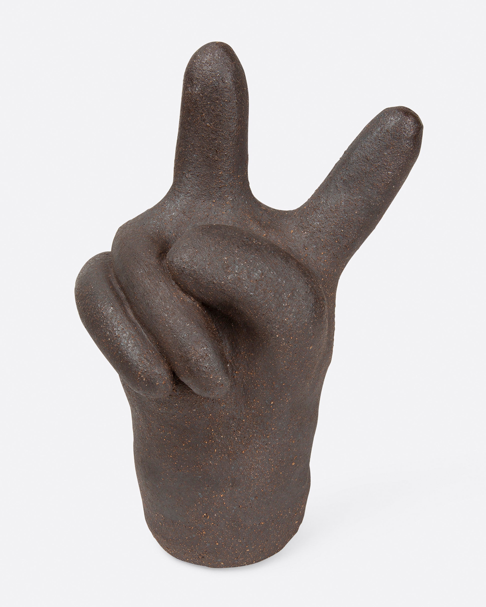 A large, dark brown peace hand sculpture, shown from the front.