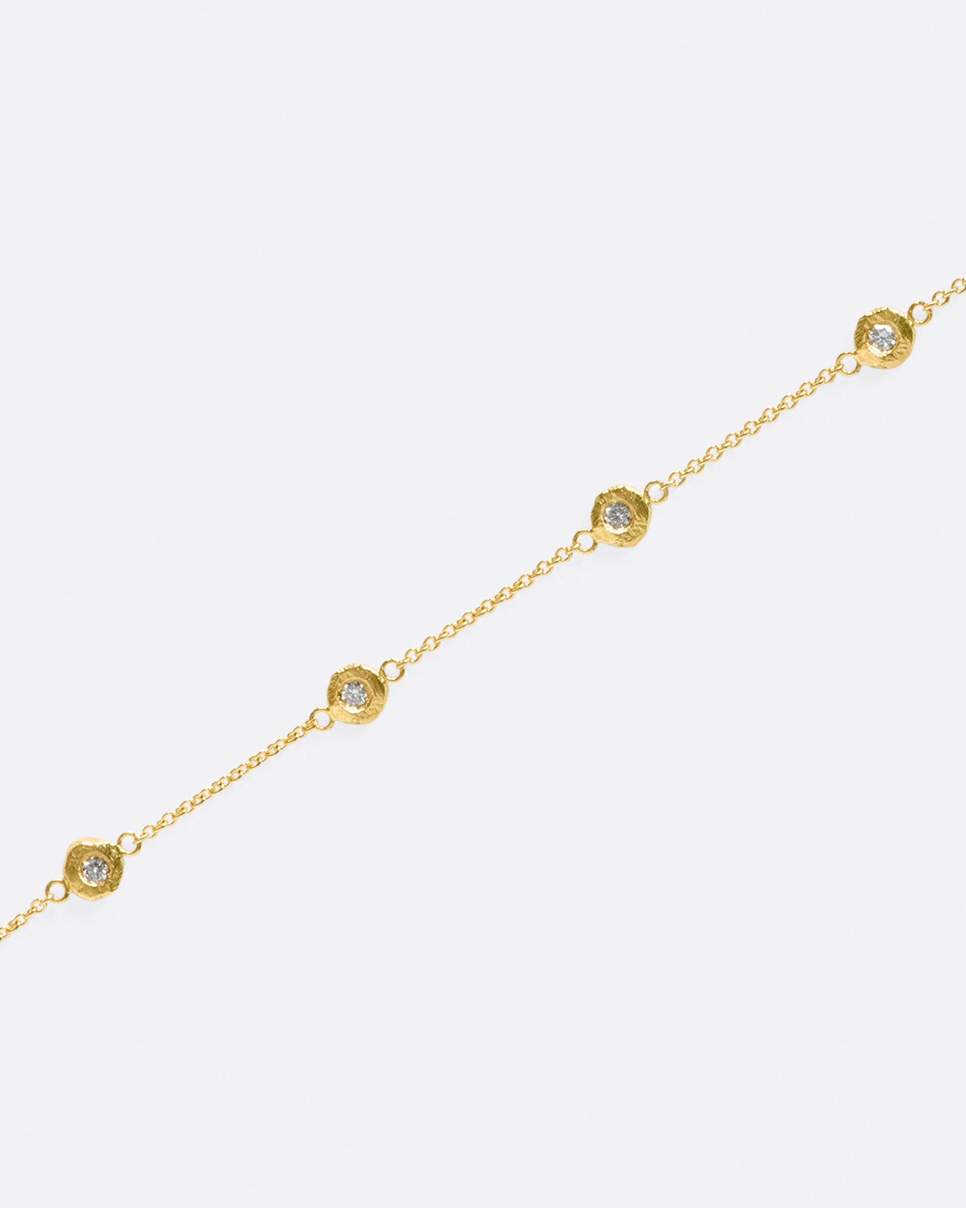 A handmade take on a classic style; this chain bracelet has five diamonds set in hand carved bezels, a bit over an inch apart.