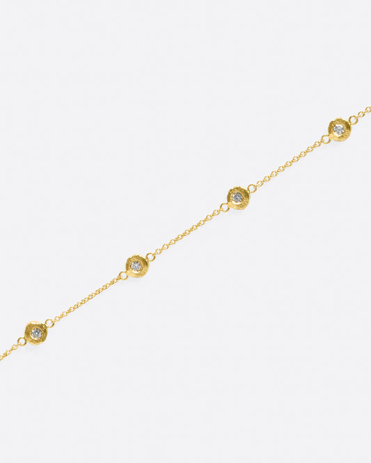 A handmade take on a classic style; this chain bracelet has five diamonds set in hand carved bezels, a bit over an inch apart.