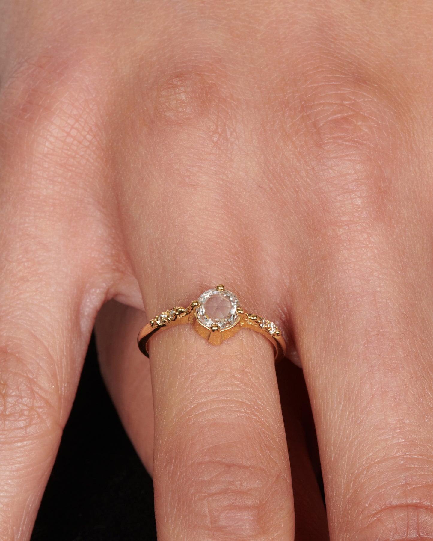 A pale champagne rose cut diamond set in four prongs with two accent diamonds on either side.
