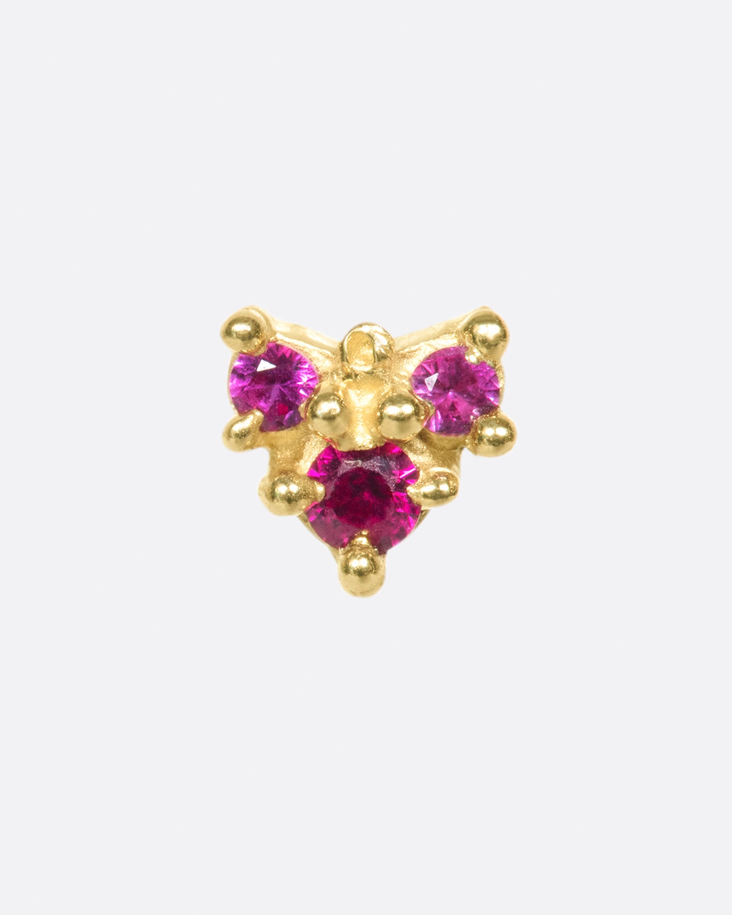 A textured arrow earring with three rosy rubies.