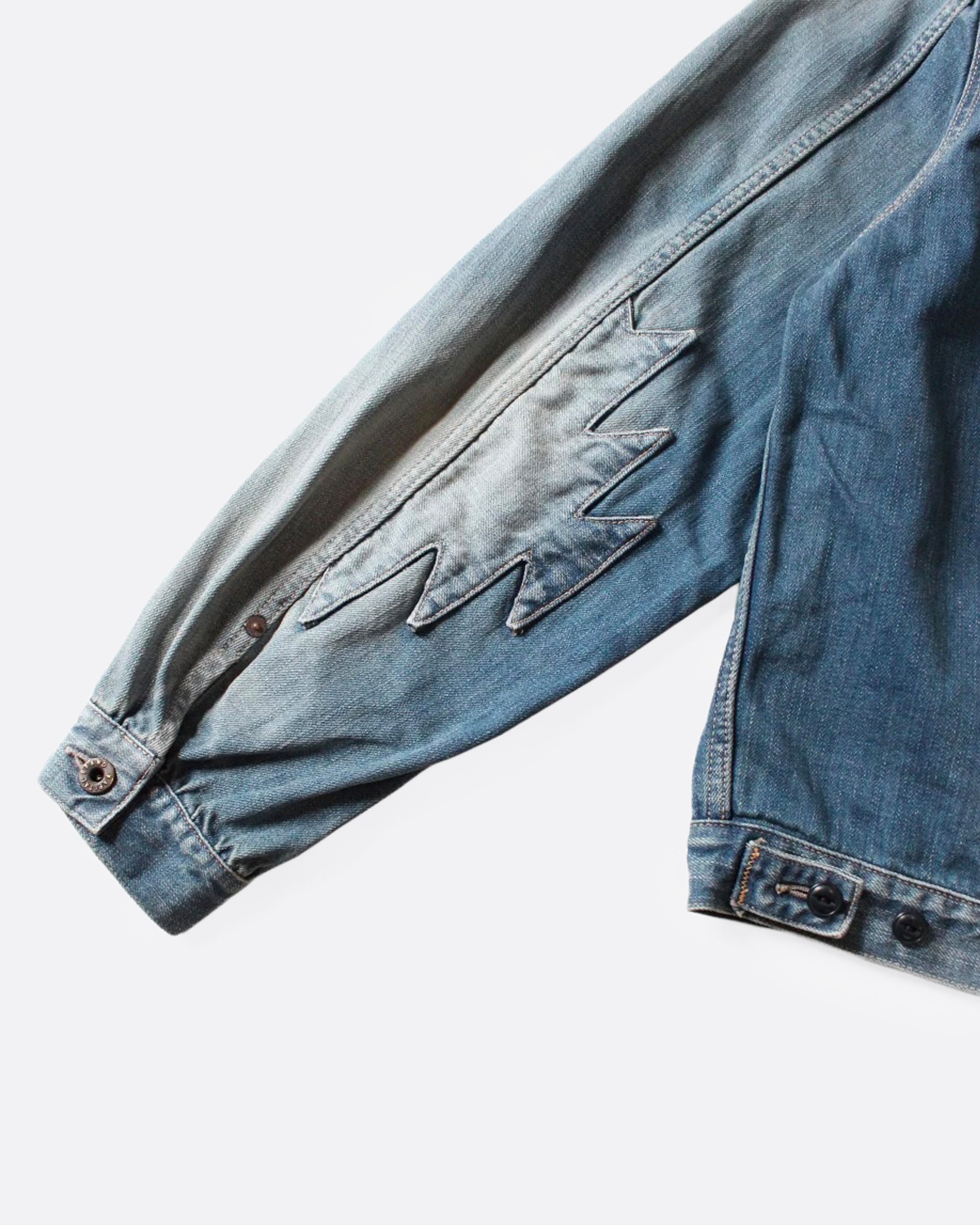 A close up of the sleeve of a light blue denim jacket with Chimayo-inspired embroidery across the chest and at each elbow.