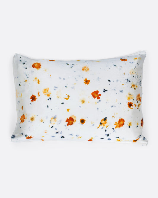 A pillow shown with a yellow and orange flower dotted silk pillowcase.