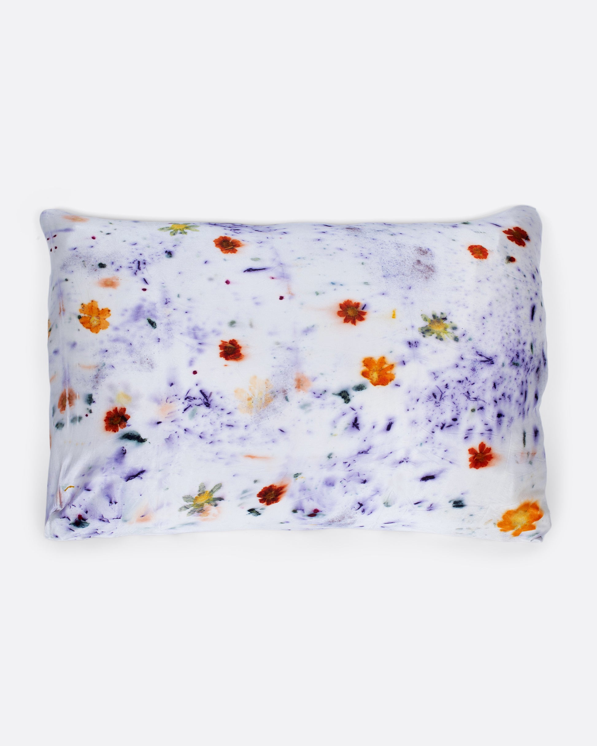 A pillow shown with a purple and orange flower dotted silk pillowcase.