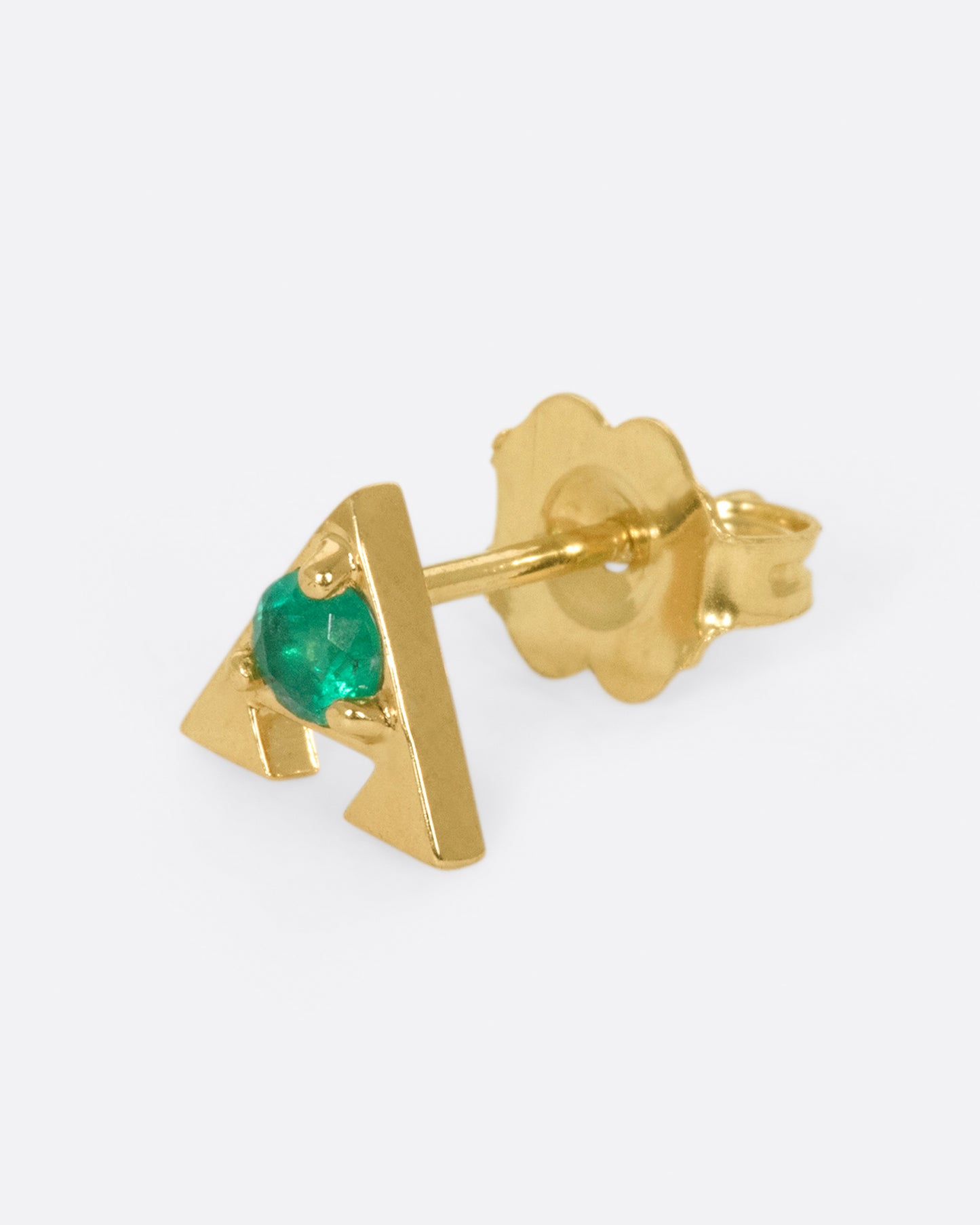 A 14k gold amulet stud with an emerald in the center