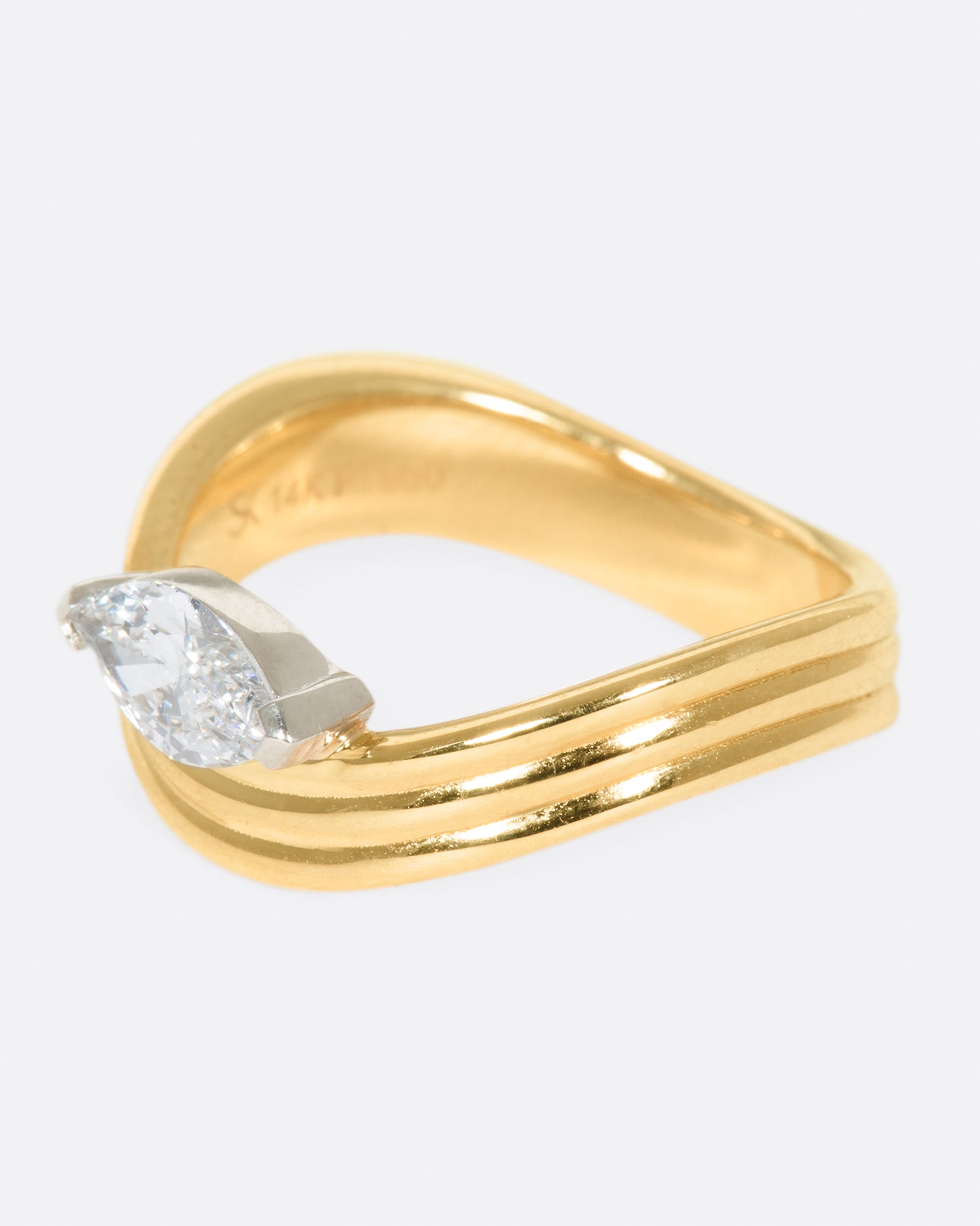 A marquise diamond is nestled into the curve of this banded ring, which sits comfortably around the base of the finger.