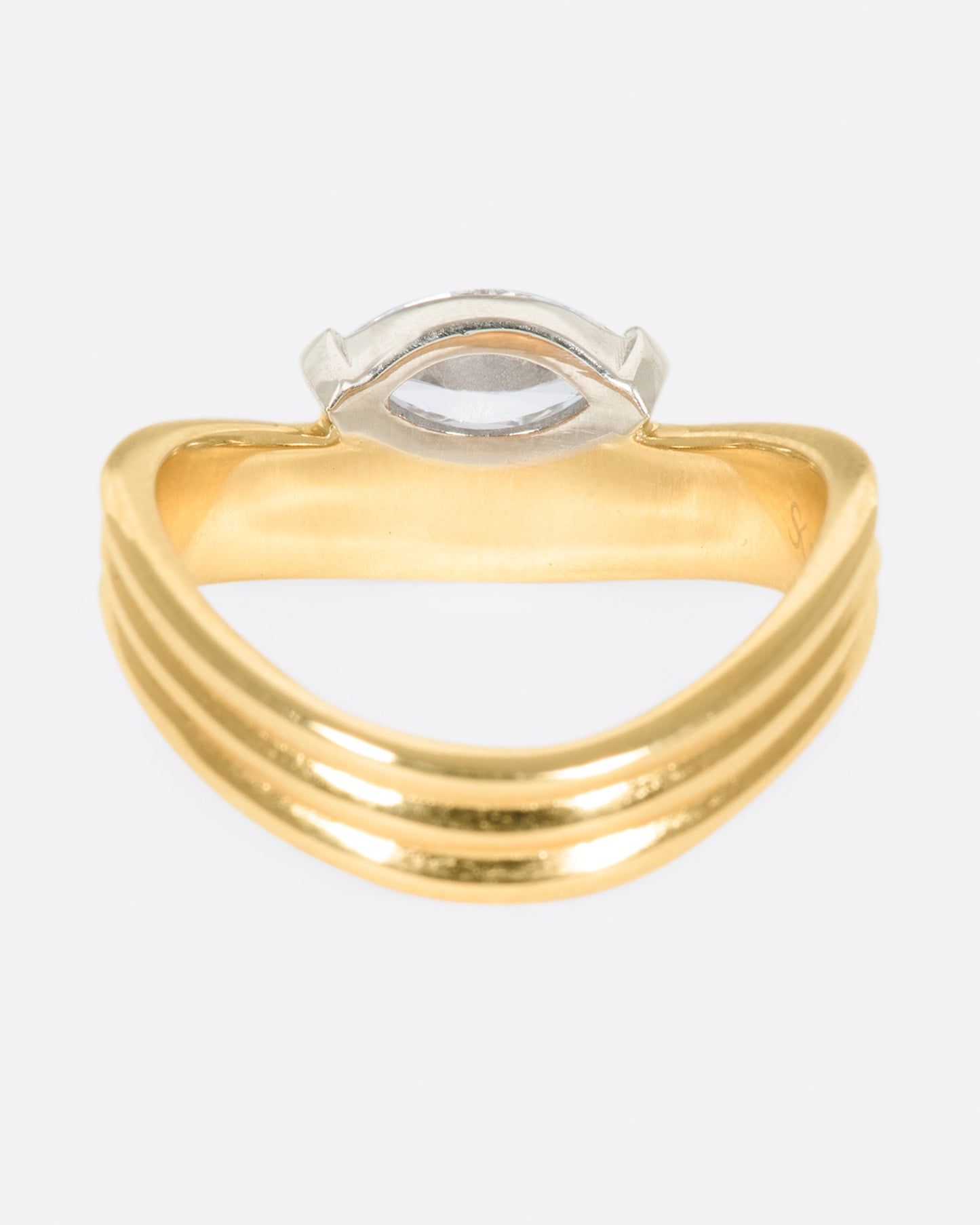 A marquise diamond is nestled into the curve of this banded ring, which sits comfortably around the base of the finger.