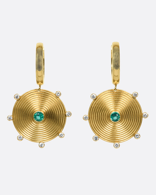 A pair of 14k gold hoops with gold disc drops, dotted with diamonds and emeralds