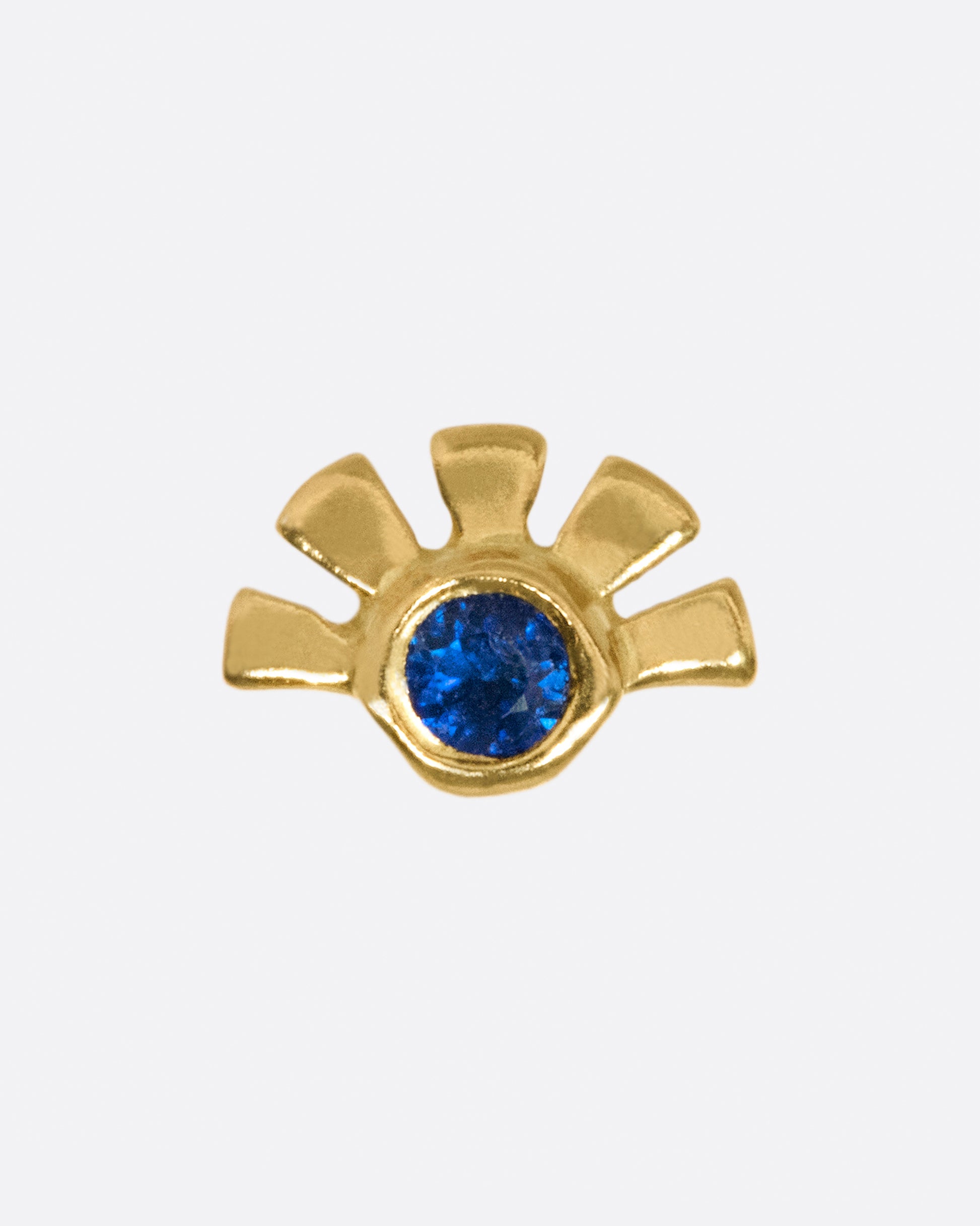 A deep blue sapphire with gold rays around one side.