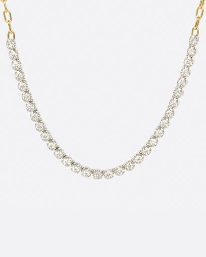 A yellow gold, oval link chain necklace with four inches of contrasting white diamonds, shown from the front.