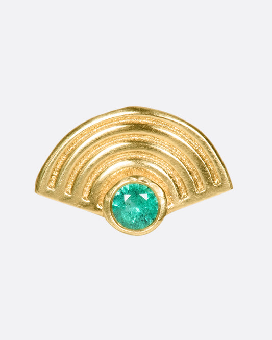 A 14k gold semi-circular spiral stud with an emerald glowing in the center