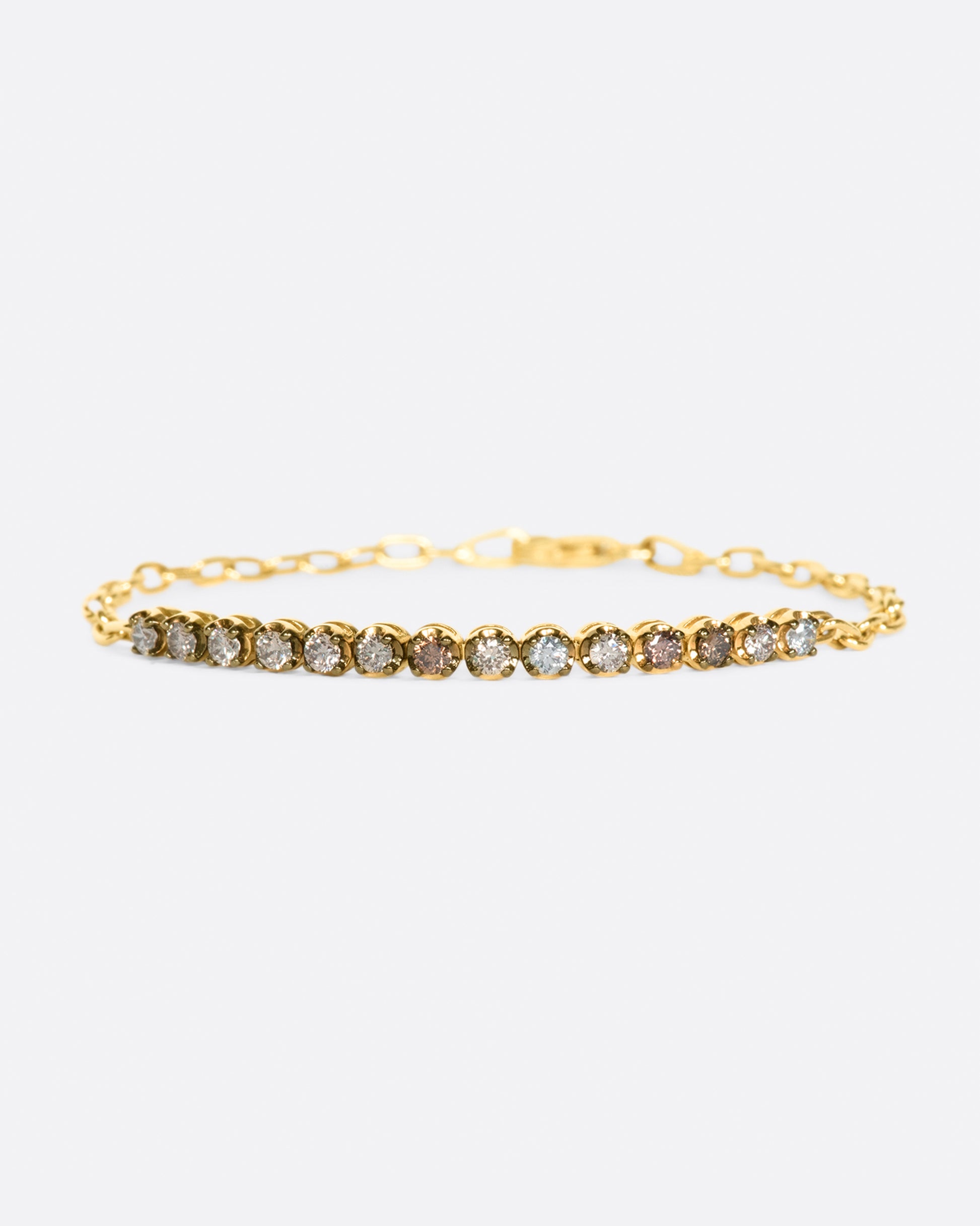 A partial tennis bracelet with a mix of light & dark champagne and gray diamonds set in darkened settings so they really glow.
