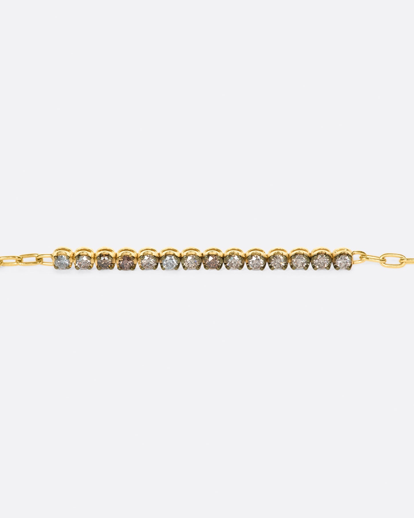 A partial tennis bracelet with a mix of light & dark champagne and gray diamonds set in darkened settings so they really glow.