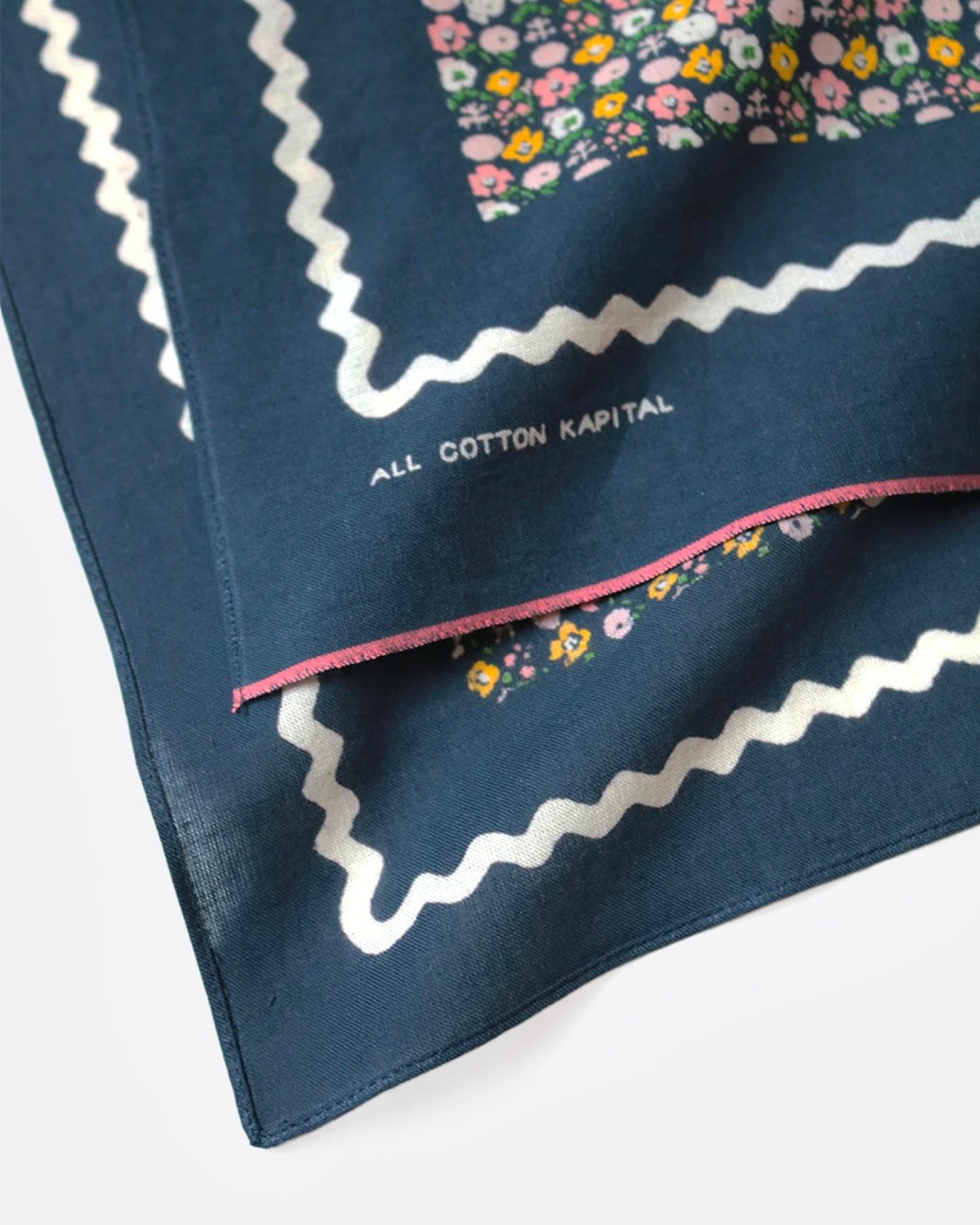 A close up of a navy blue bandana with a ditsy floral print and tiny skulls throughout.