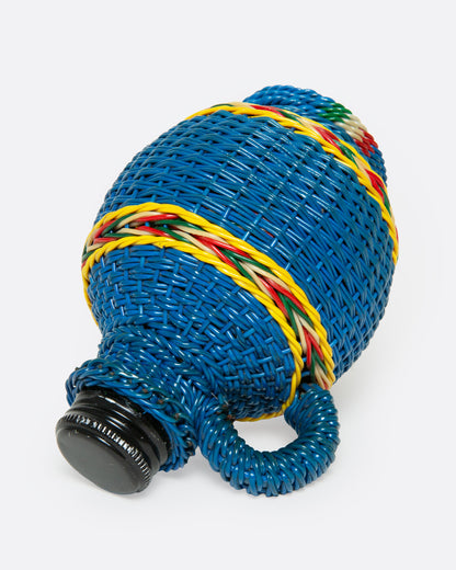 A glass Hungarian Miner's Bottle with a colorful pattern of woven electrical wire on top, shown from the side.