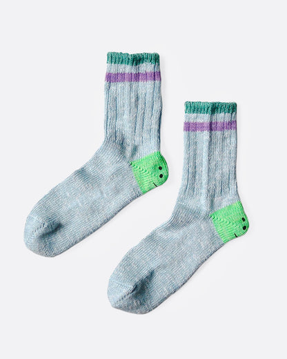 A pair of blue socks with green smiley heels, and green and purple stripes on each ankle. Shown from the side.