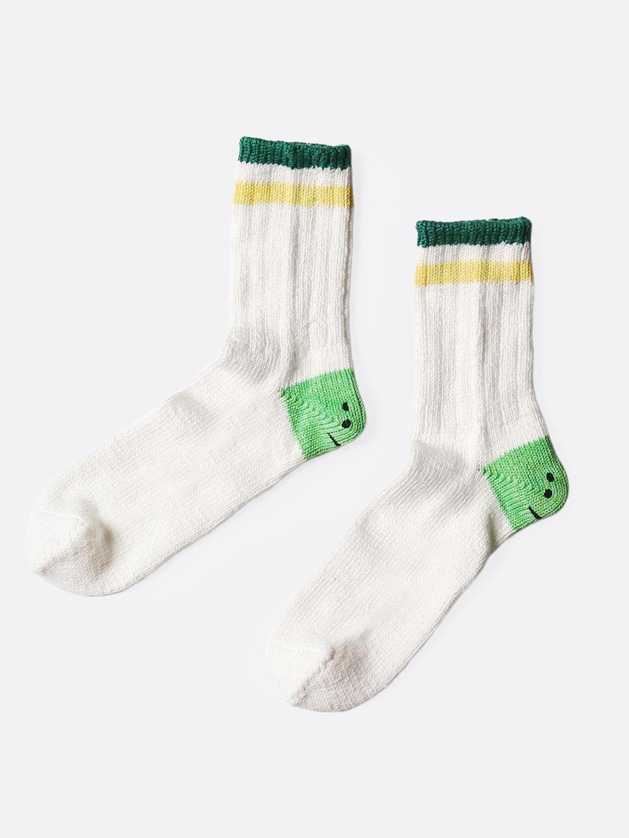 A pair of white socks with green smiley heels, and yellow and green stripes on each ankle. Shown from the side.