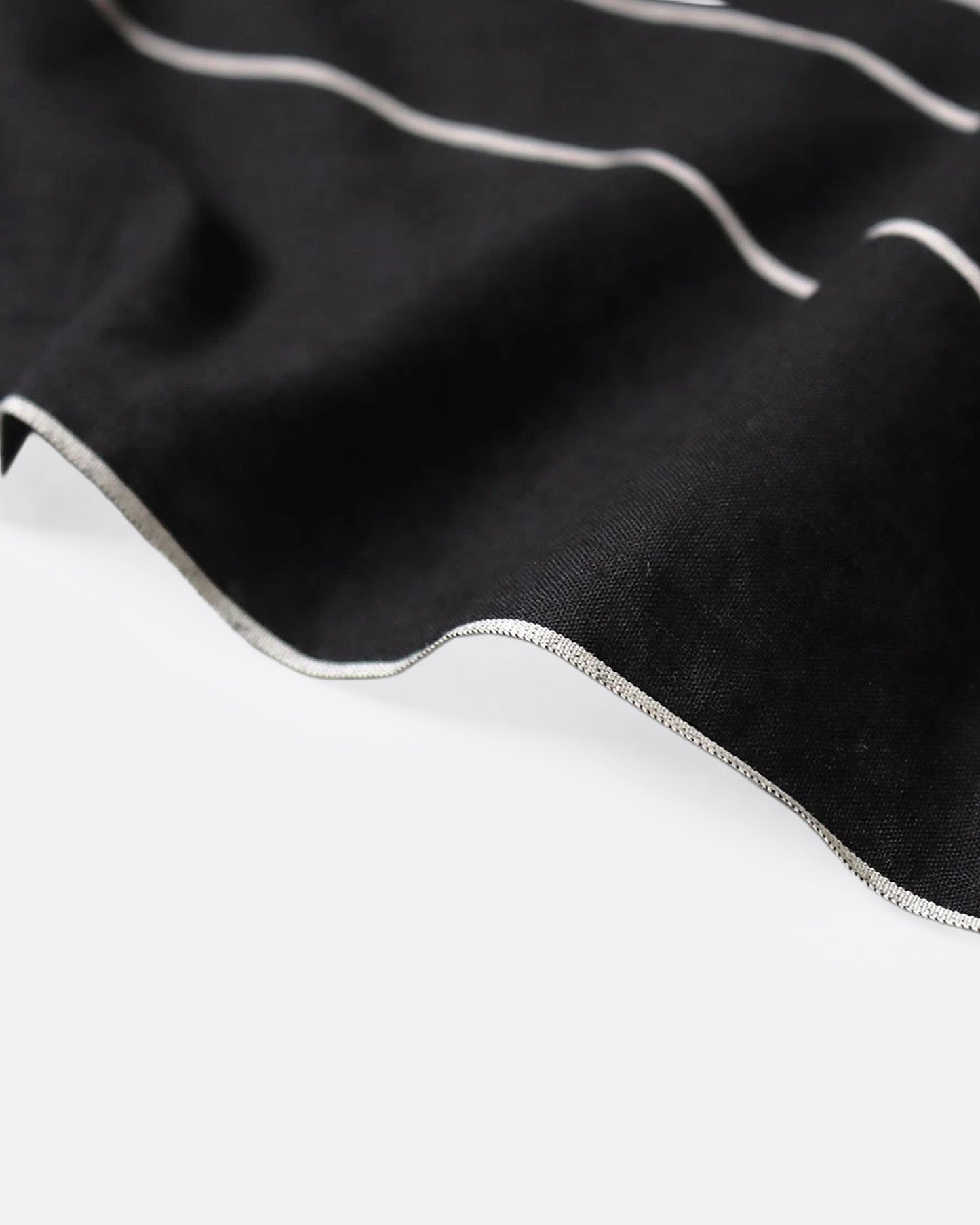 A close up of the edge of a black bandana with a white spider web and two colorful patch graphics in one corner.