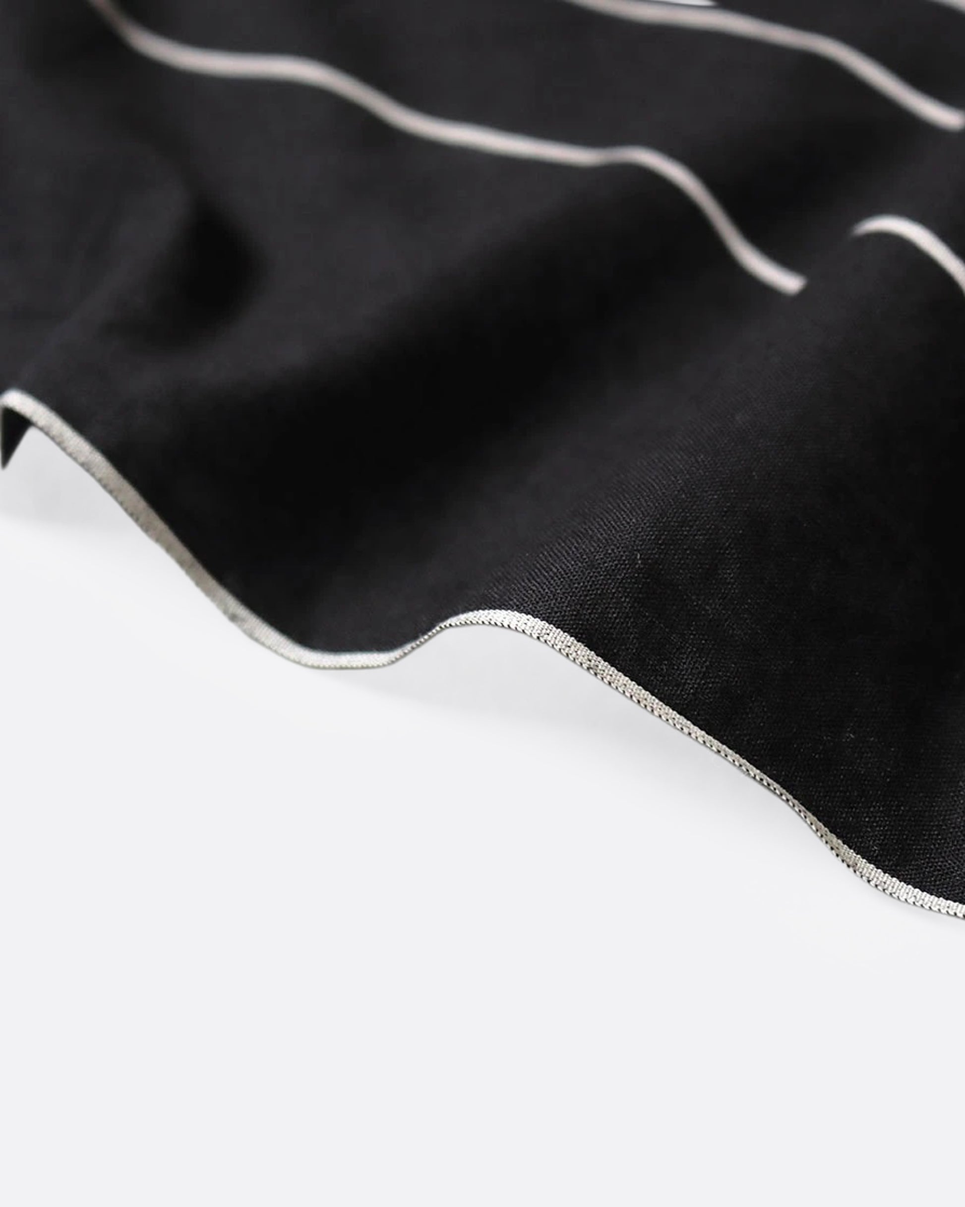 A close up of the edge of a black bandana with a white spider web and two colorful patch graphics in one corner.