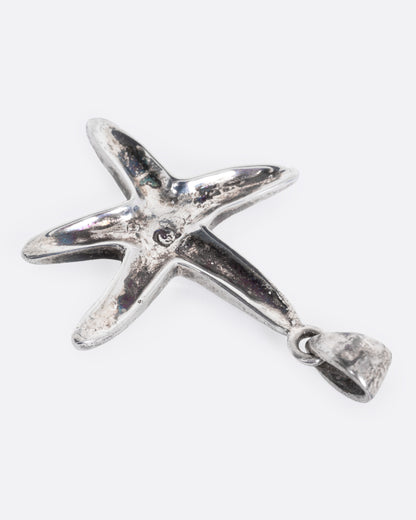 A silver starfish pendant with opal inlay show from the back.