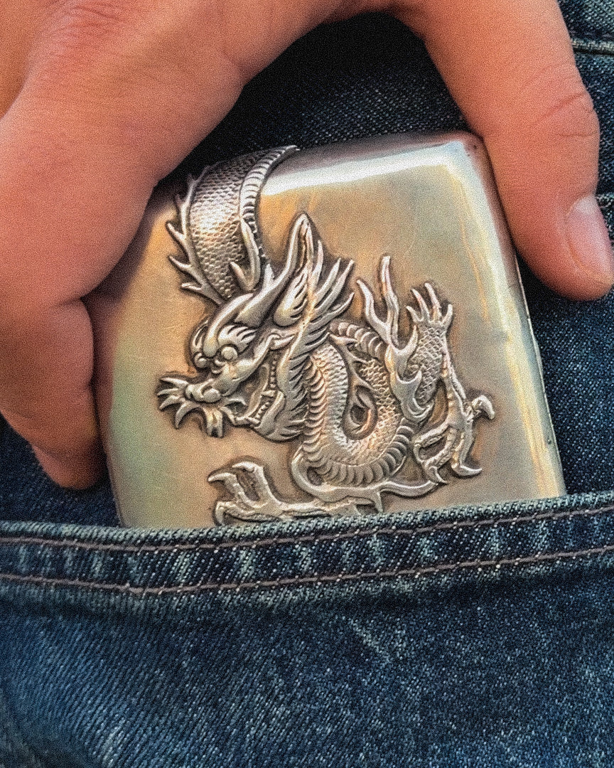 A silver box with a wagon on it, shown being pulled from a jean pocket.
