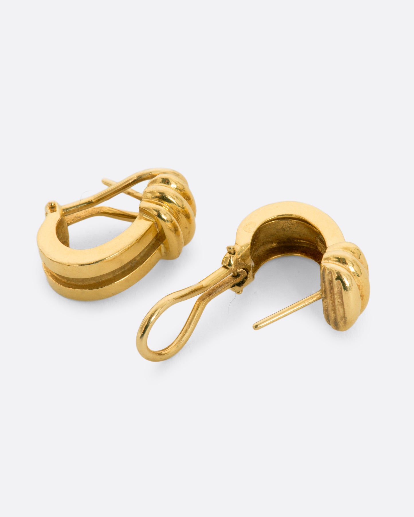 Yellow gold J-shaped earrings with omega backings. View from the side, alternating, showing the closure.