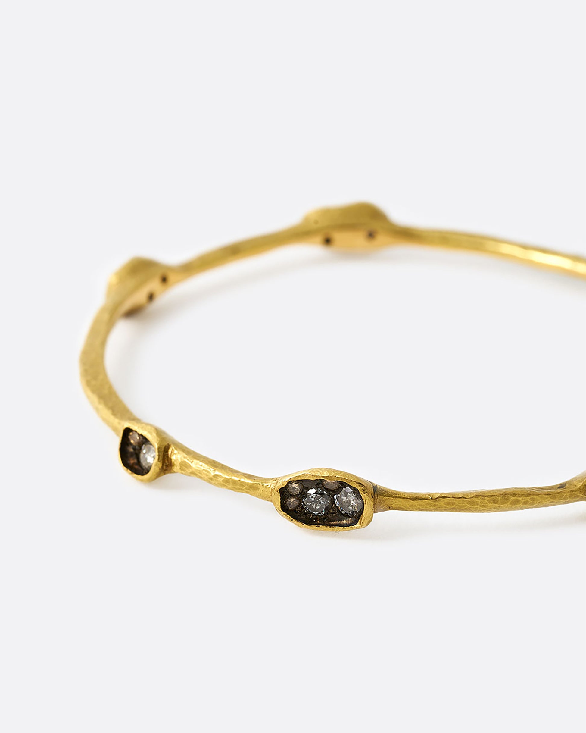 Yellow gold bangle bracelet with diamonds in oval settings, shown from the side.