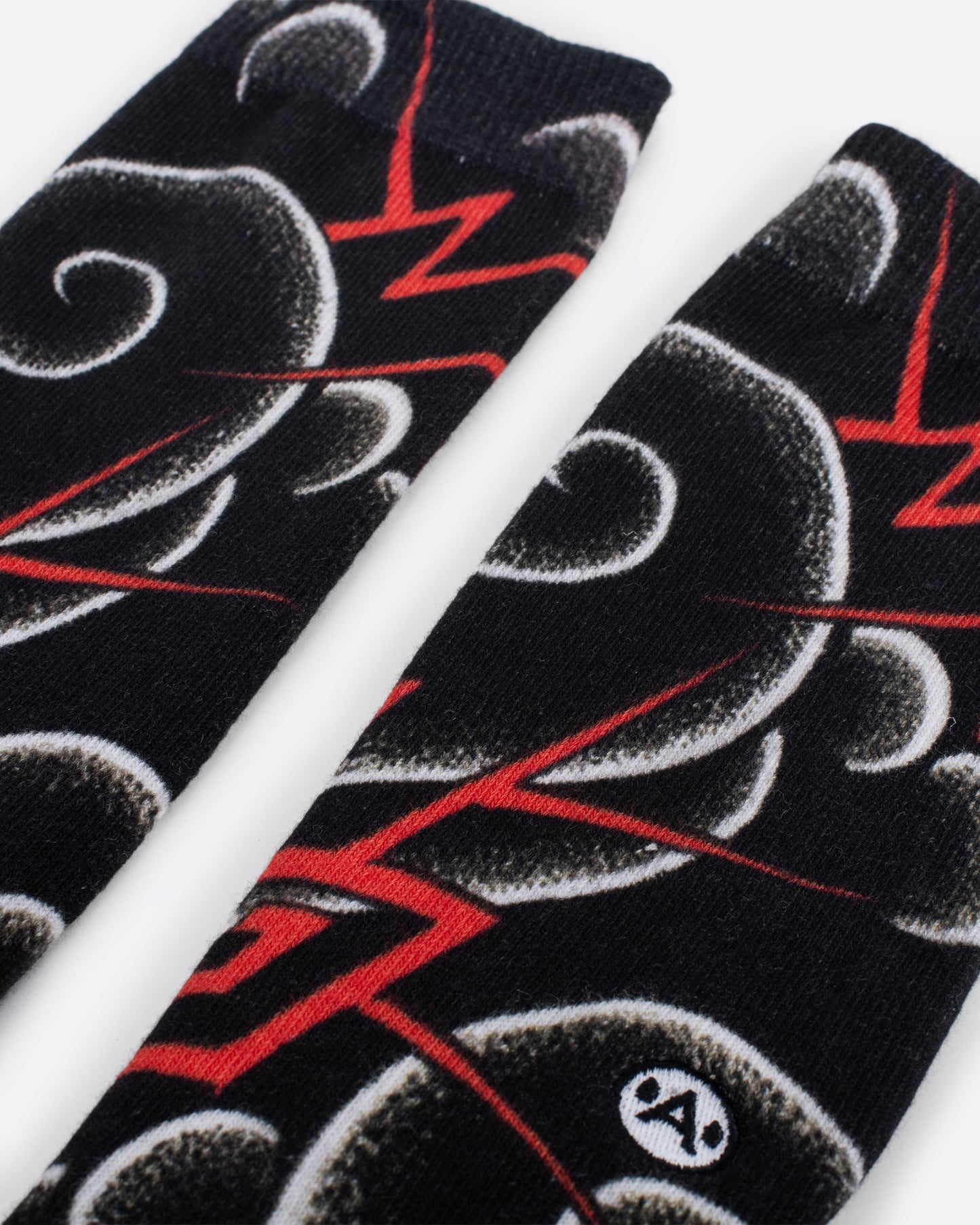 Black socks with white and red rounded and geometric swirl patterns. Close up view..