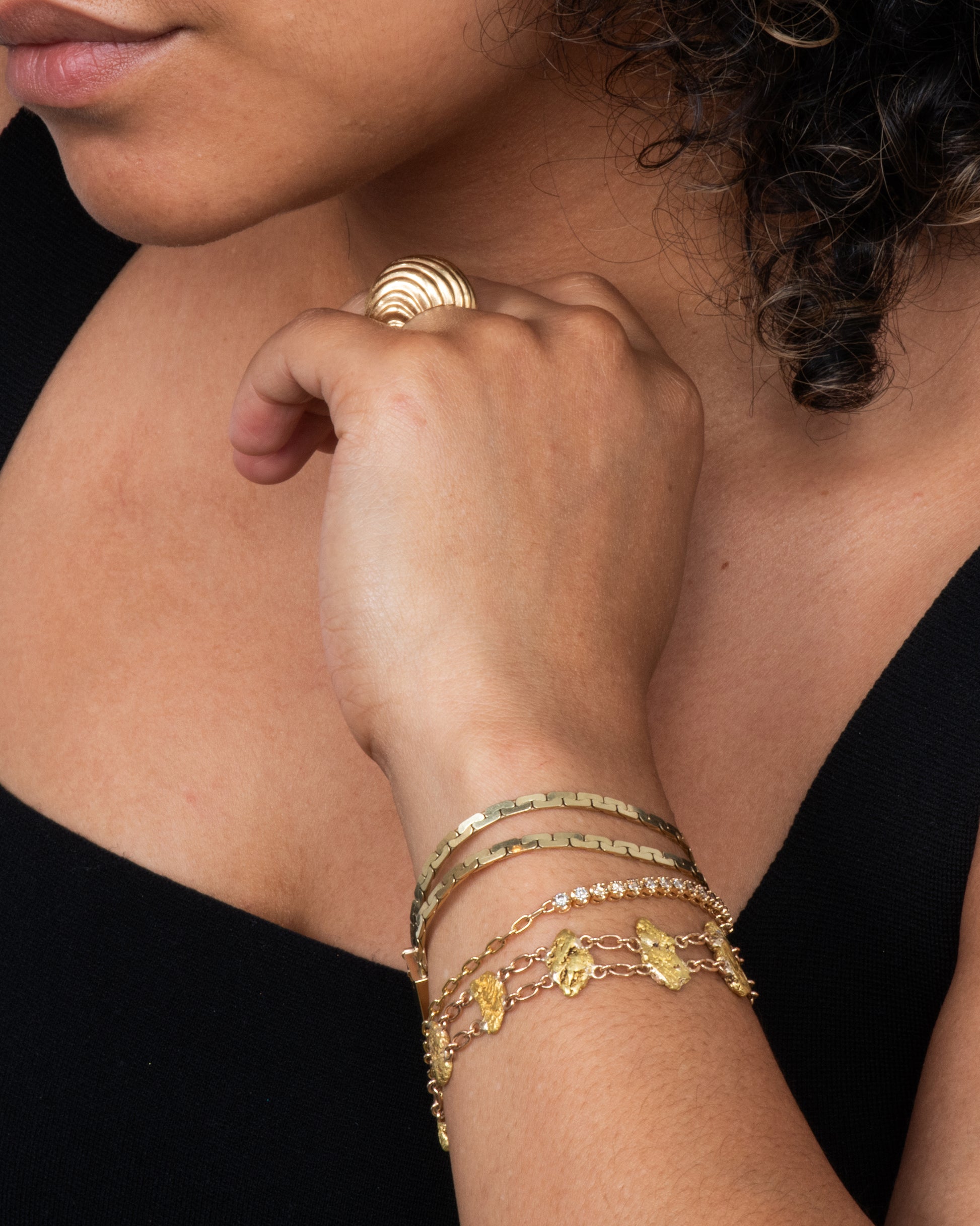 A yellow gold nugget bracelet featuring nine solid nuggets. View on an arm.