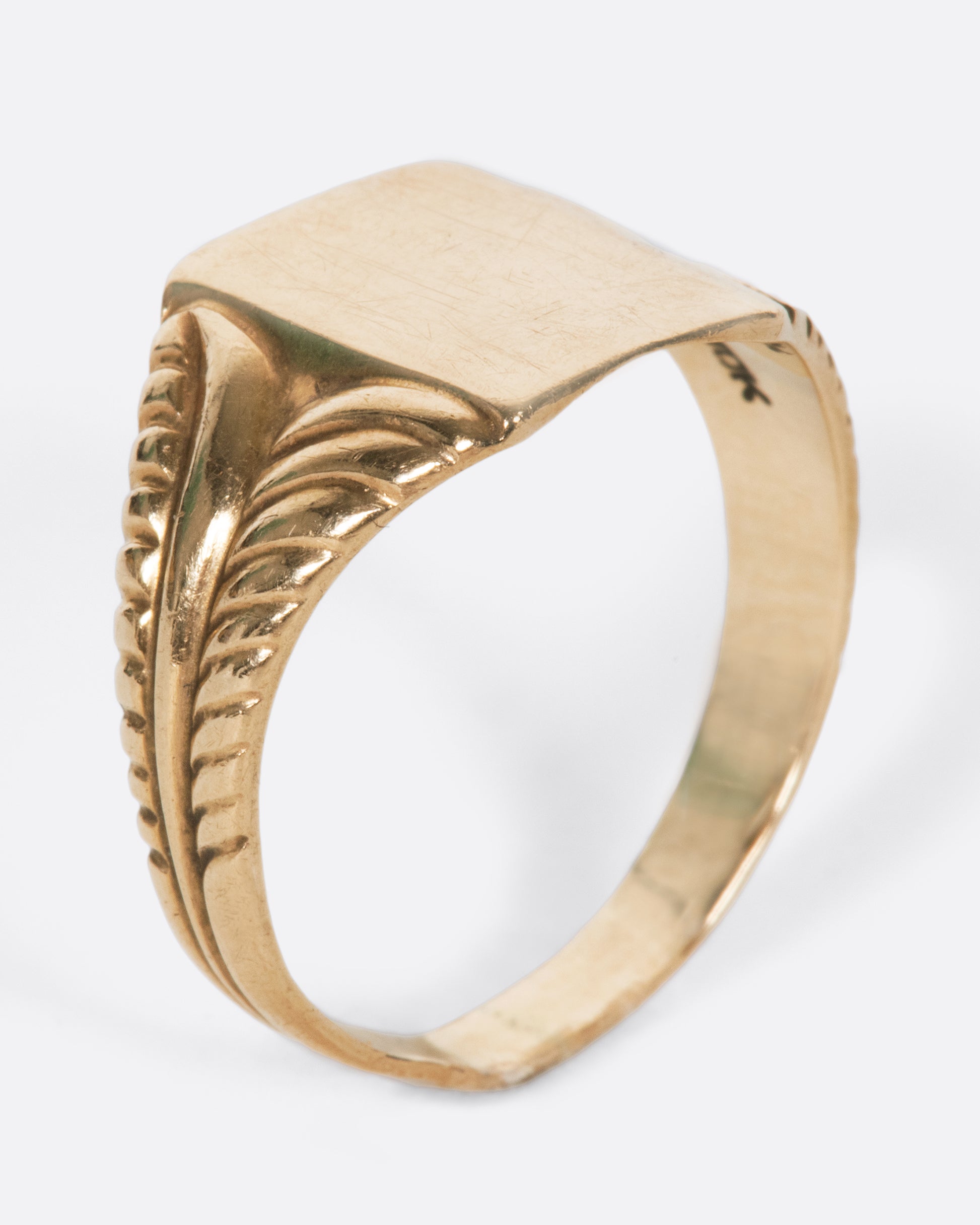 A vintage yellow gold rectangular signet ring with textured shoulders and a blank face.
