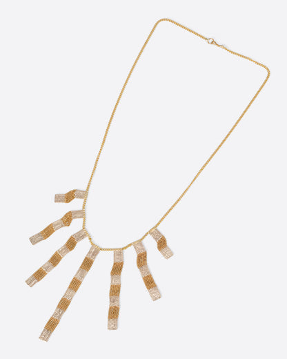 A yellow gold cable chain necklace with seven clusters of cable chain fringe with alternating bits of silver solder. Shown from the front.