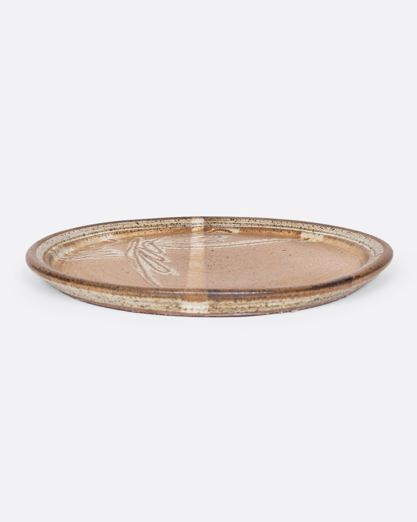 This speckled glaze, studio-made serving platter has a light line and sprawling bow-like scribble design. 