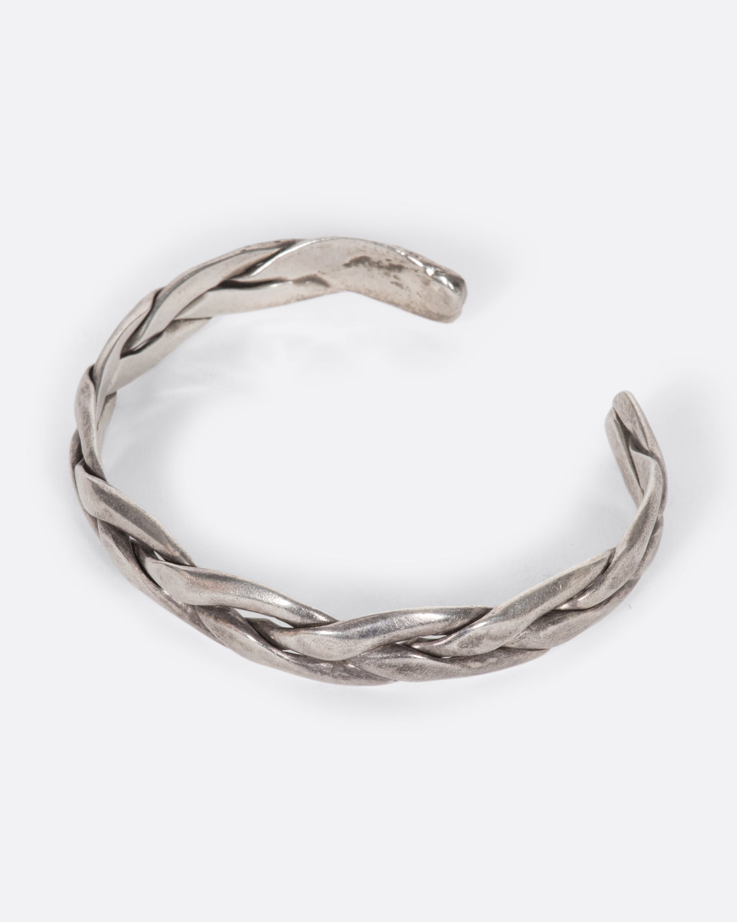 A vintage sterling silver cuff bracelet made from three braided strands of silver. Shown from above.