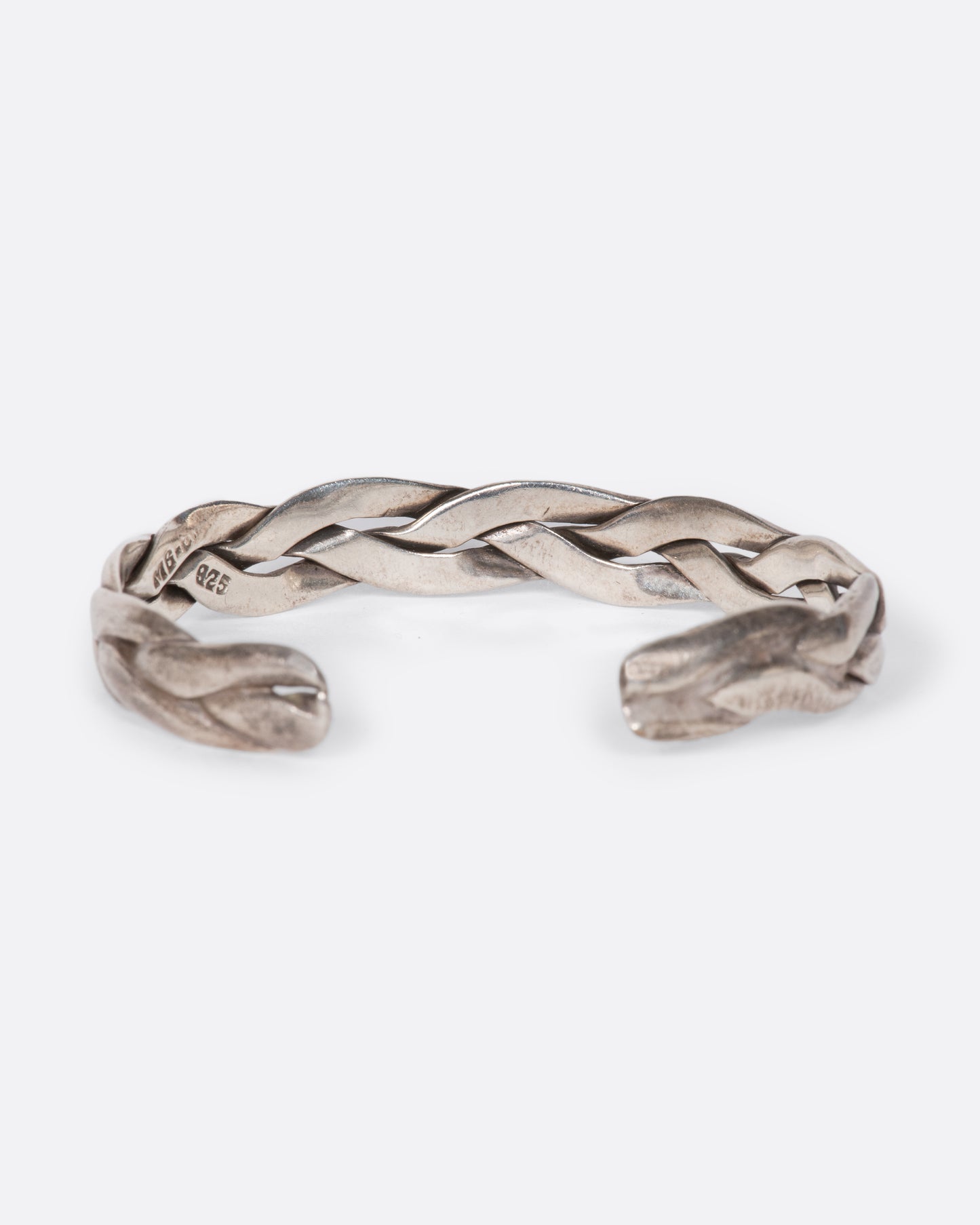 A vintage sterling silver cuff bracelet made from three braided strands of silver. Shown from behind.